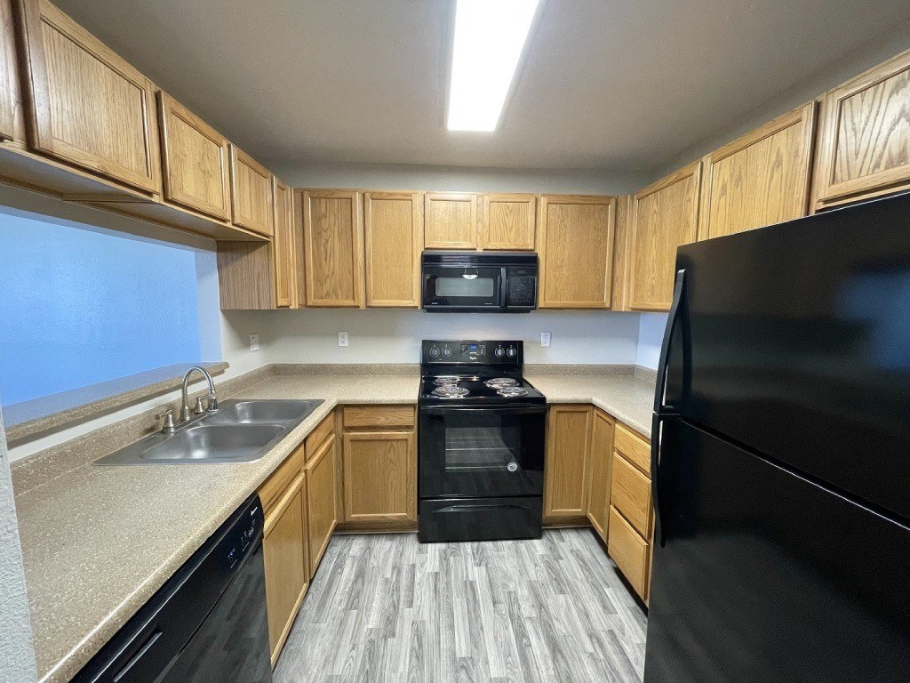 A kitchen with black appliances and wooden cabinets.